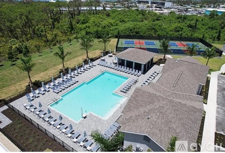 An outdoor swimming pool surrounded by sun loungers and trees.
