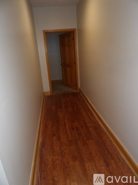 A hallway with a wooden floor and a door.