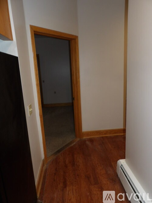 A room with a wooden floor and a door leading to another room.