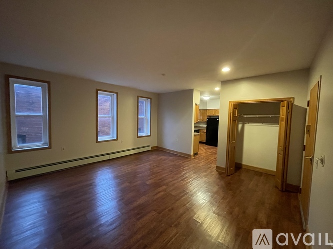 A spacious room with wooden floors and a large mirror on the wall.