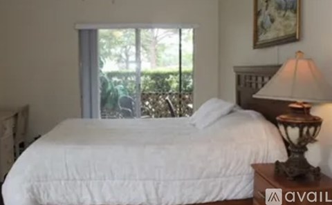 A bedroom with a large bed and a lamp on a side table.