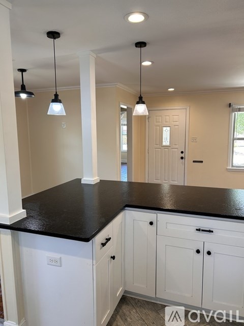 A kitchen with white cabinets and a black countertop.