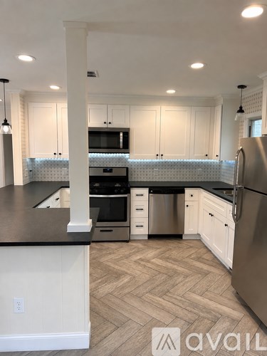 A kitchen with a black countertop and a stainless steel refrigerator.