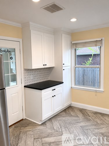 A kitchen with white cabinets and a black countertop.