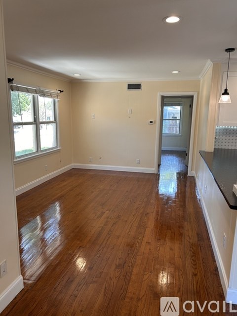 A room with wooden floors and a door leading to another room.