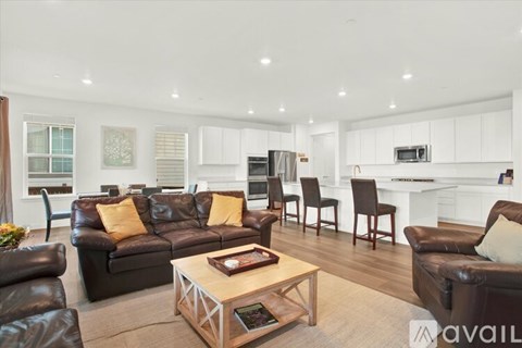 A living room with a black leather couch and a wooden coffee table.