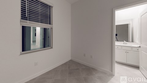 A room with a window and a door leading to a bathroom.