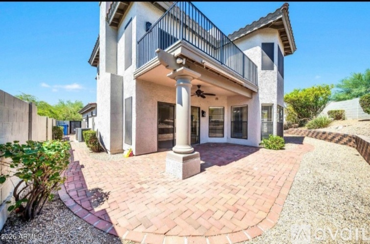 A house with a balcony and a brick walkway in front.