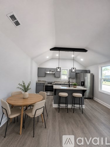 A kitchen with a table and chairs in the foreground and a window in the background.