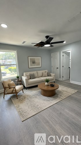 A living room with a white couch, a coffee table, and a ceiling fan.