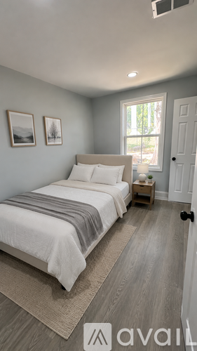 A bedroom with a bed, nightstand, and two pictures on the wall.