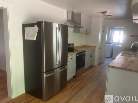 A kitchen with a stainless steel refrigerator and wooden floors.