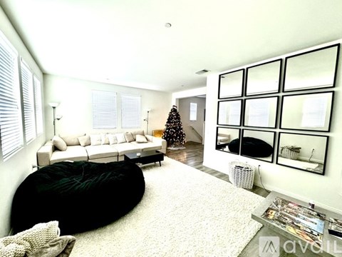A living room with a white couch, a black bean bag, and a coffee table with magazines on it.