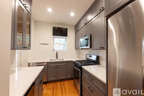 A modern kitchen with a stainless steel refrigerator and wooden floors.
