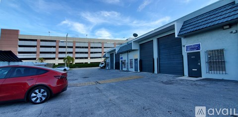 A red car is parked in front of a building with a sign that says "available".