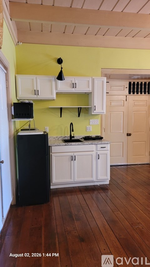 A kitchen with yellow walls and white cabinets.