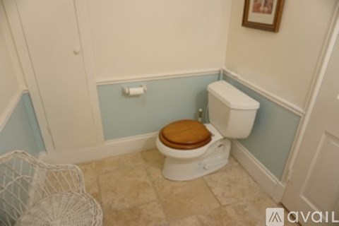A toilet with a wooden seat is in a bathroom with blue walls.