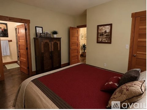 A bedroom with a large bed and a wooden cabinet.