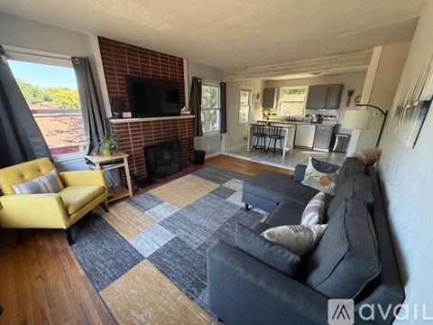 A living room with a yellow couch and a grey couch with a checkered rug in between.