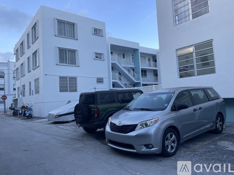 A silver car is parked in front of a white building.