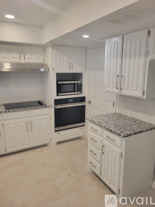 A kitchen with white cabinets and a granite countertop.