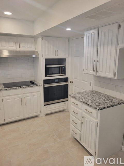 A kitchen with white cabinets and a granite countertop.