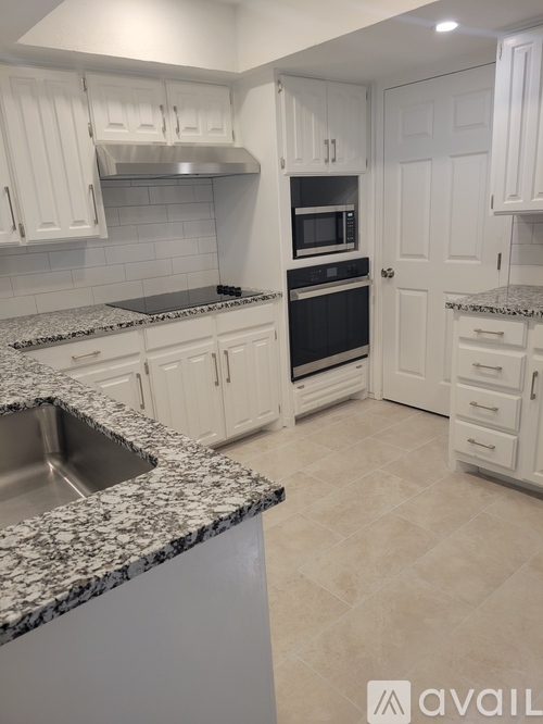 A kitchen with granite countertops and white cabinets.