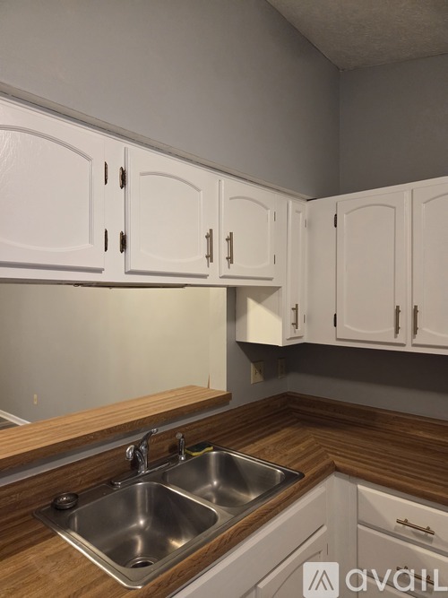 A kitchen with white cabinets and a wooden counter top.