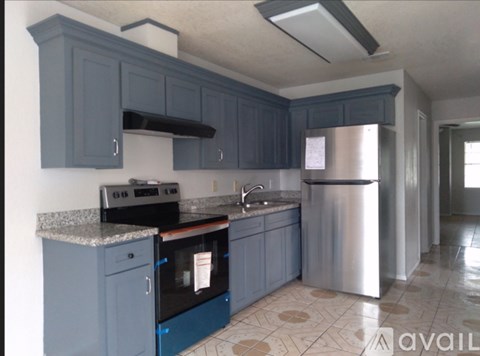 A kitchen with blue cabinets and a stainless steel refrigerator.