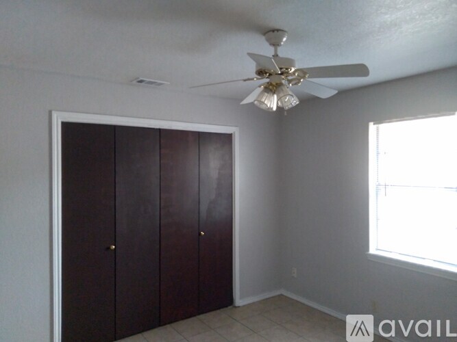 A room with a ceiling fan and a window with a view of a building outside.