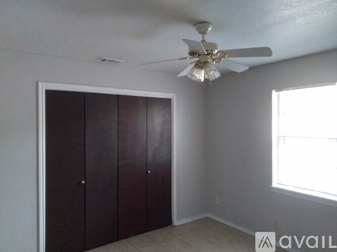 A room with a ceiling fan and a window with a view of a building outside.