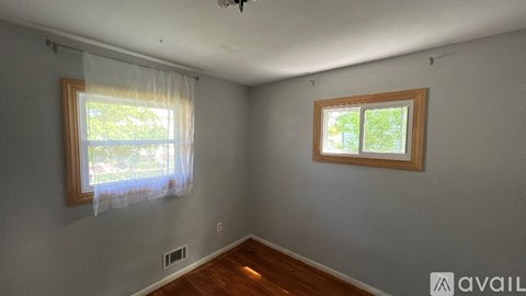 A room with two windows and a ceiling fan.