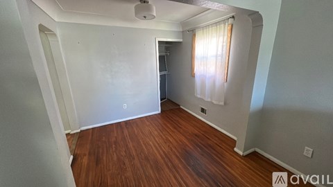 A room with wooden floors and a window with curtains.