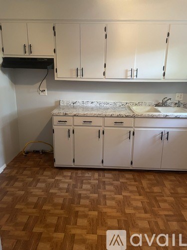 A kitchen with white cabinets and a wooden floor.