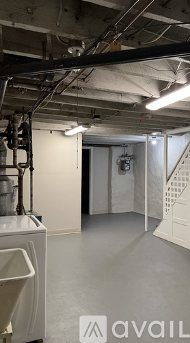A large, empty industrial space with a washing machine on the left and a staircase on the right.