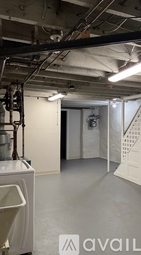 A large, empty industrial space with a washing machine on the left and a staircase on the right.