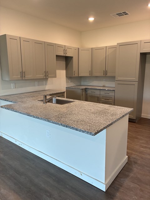 A kitchen with a granite countertop and white cabinets.