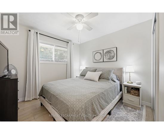 A bedroom with a bed, nightstand, and a ceiling fan.