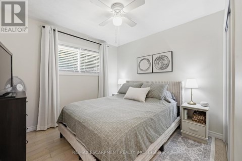 A bedroom with a bed, nightstand, and a ceiling fan.