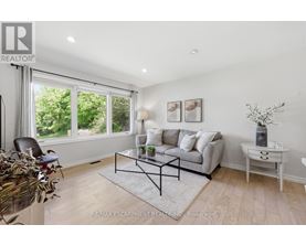 A living room with a grey couch, a glass coffee table, and a white side table.