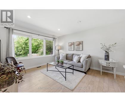 A living room with a grey couch, a glass coffee table, and a white side table.