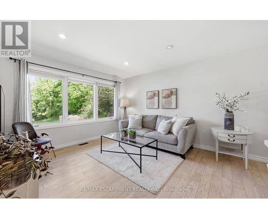 A living room with a grey couch, a glass coffee table, and a white side table.