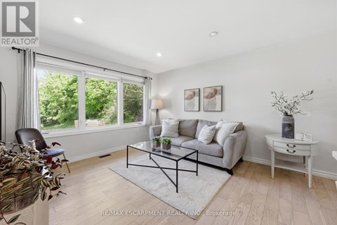 A living room with a grey couch, a glass coffee table, and a white side table.