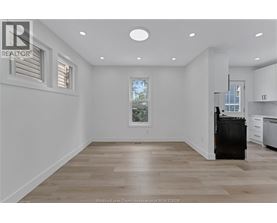 A spacious kitchen with a black fridge and wooden flooring.