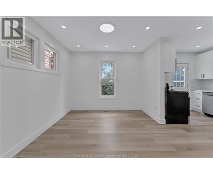 A spacious kitchen with a black fridge and wooden flooring.