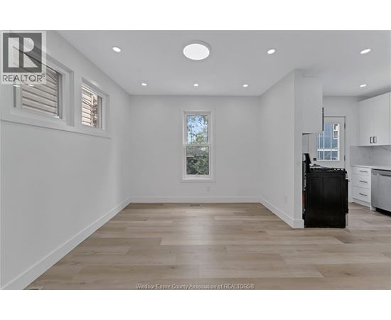 A spacious kitchen with a black fridge and wooden flooring.