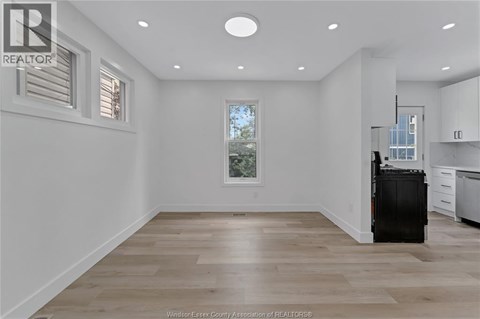 A spacious kitchen with a black fridge and wooden flooring.