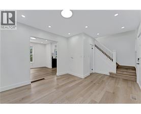 A spacious room with wooden flooring and a staircase leading to another room.
