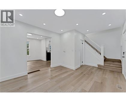 A spacious room with wooden flooring and a staircase leading to another room.