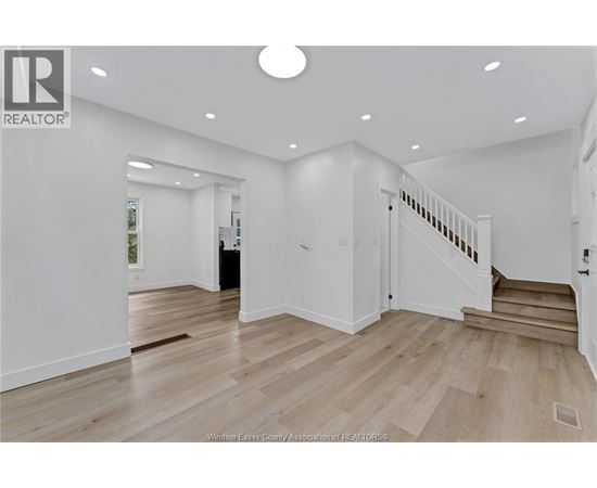 A spacious room with wooden flooring and a staircase leading to another room.